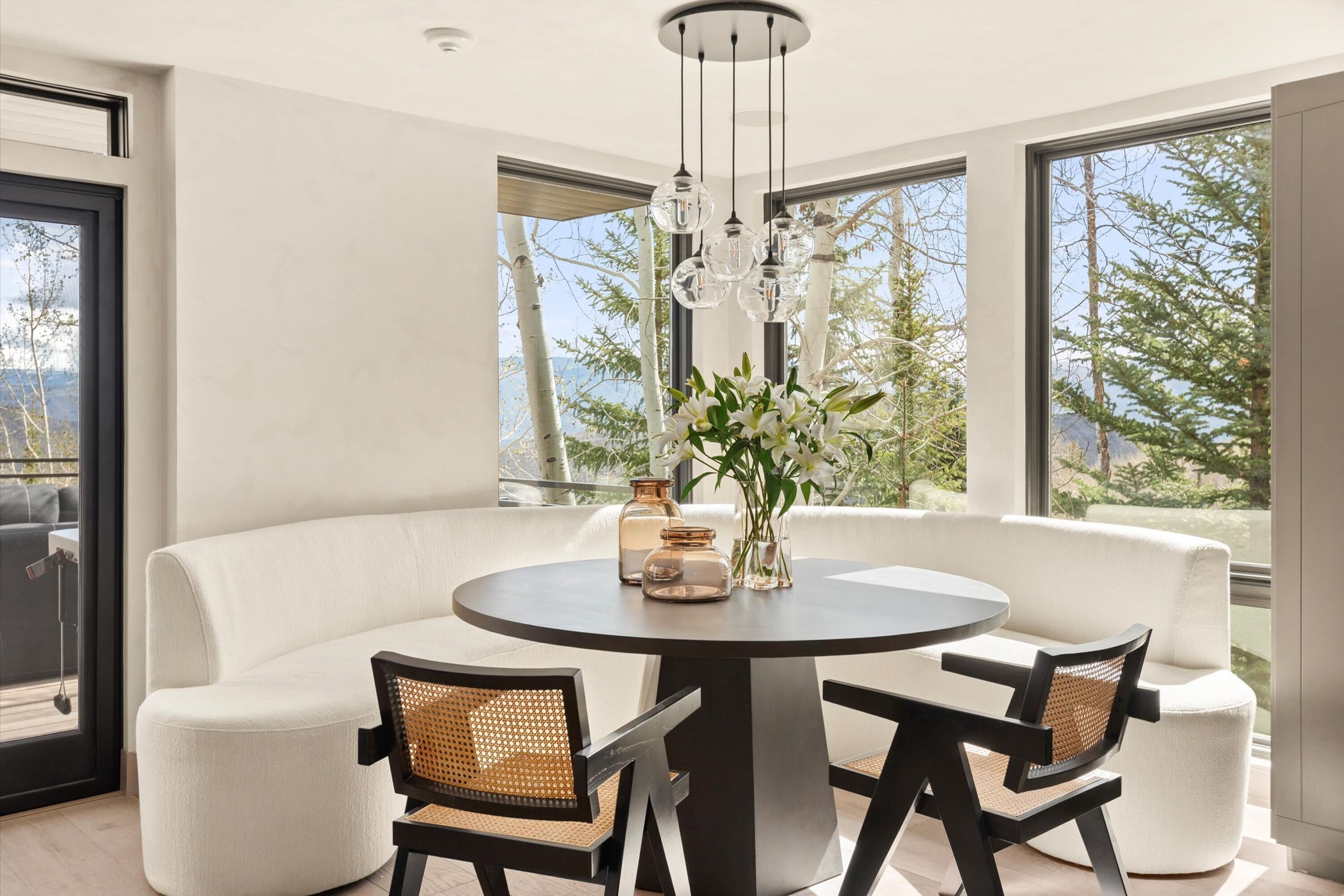 A modern dining area with a round table, two chairs, and a vase of flowers.