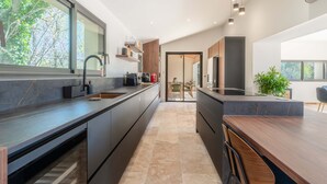 A modern kitchen with a large island, built-in appliances, and a view of the outdoors. - Villa de l Ecluse Maussane les Alpilles (Maussane-les-Alpilles)