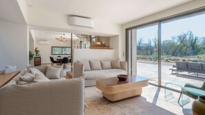 A modern living room with a sofa, coffee table, and dining area. There is a staircase leading to an upper level. - Villa de l Ecluse Maussane les Alpilles (Maussane-les-Alpilles)