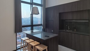 Eine moderne Küche mit einer großen Kochinsel, Barhocker, einem Einbauofen und Blick auf die Stadt durch große Fenster.