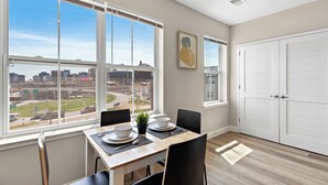 A dining area with a table set for two, large windows offering a city view, and a white closet with louvered doors. - City Views 1BR Free-Parking- Close to NYC (Newark)