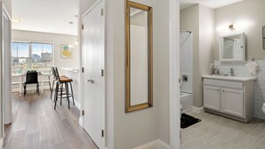 A modern apartment with a dining area, a large mirror, and a bathroom with a vanity. - City Views 1BR Free-Parking- Close to NYC (Newark)