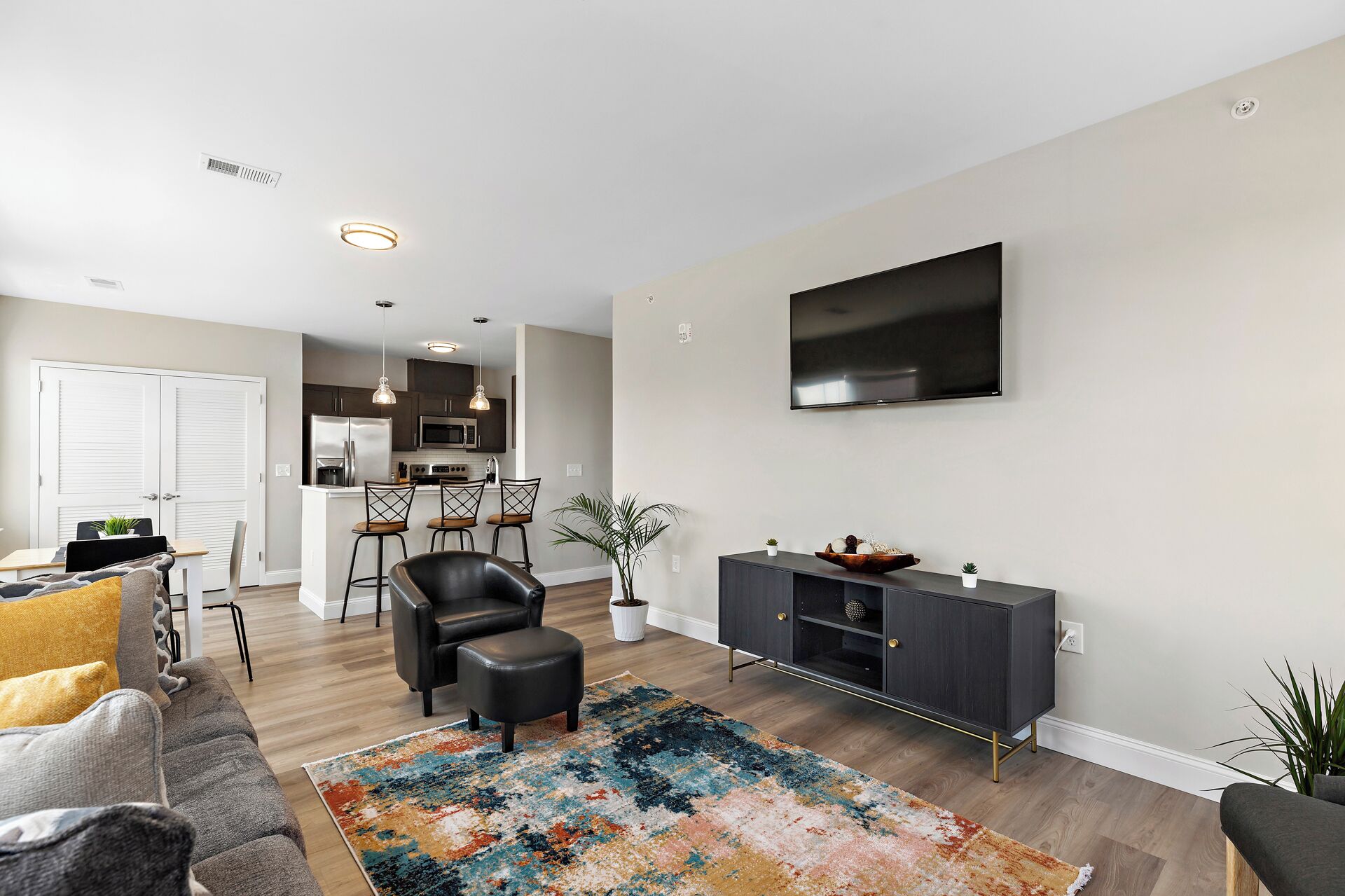 A modern living room with a sofa, a coffee table, a TV, and a kitchen in the background.