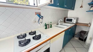 A compact kitchen with a gas stove, microwave, and a sink. - Cataldo guest house Capri center (Marina Grande)