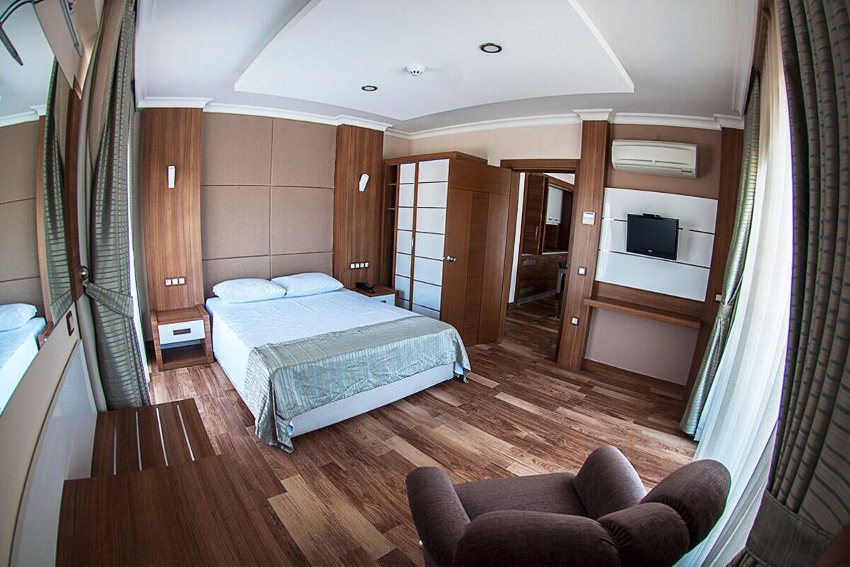 A modern hotel room with a large bed, a TV, and a wooden wardrobe.
