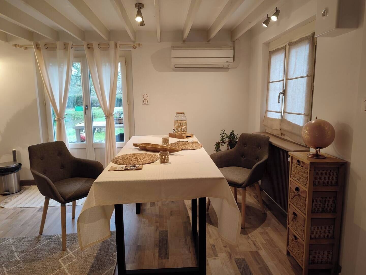 Comedor con una mesa dispuesta para dos personas, dos sillas, un globo terráqueo y un radiador.