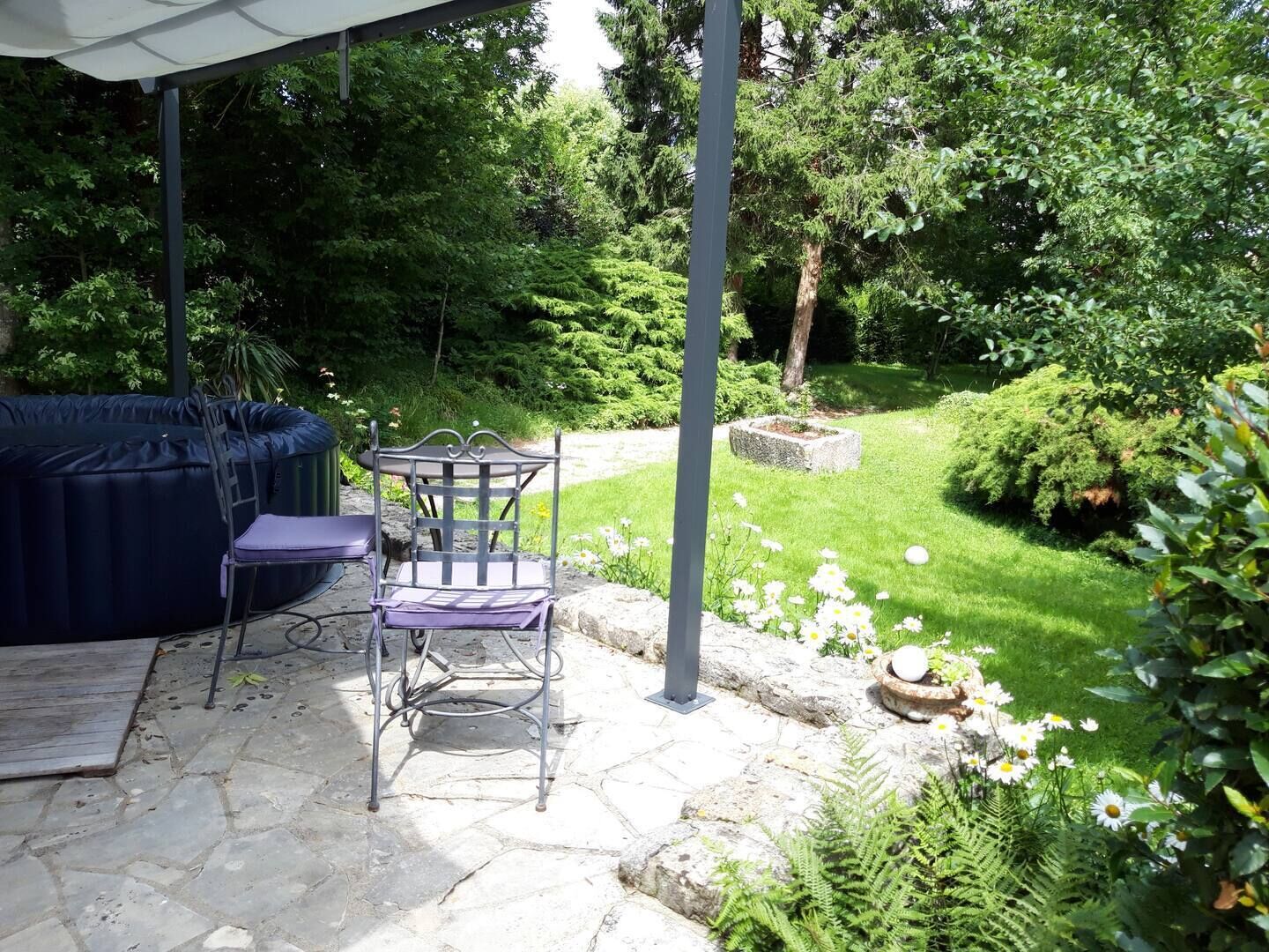 An outdoor patio with a stone floor, a metal table and chair, and a blue sofa.
