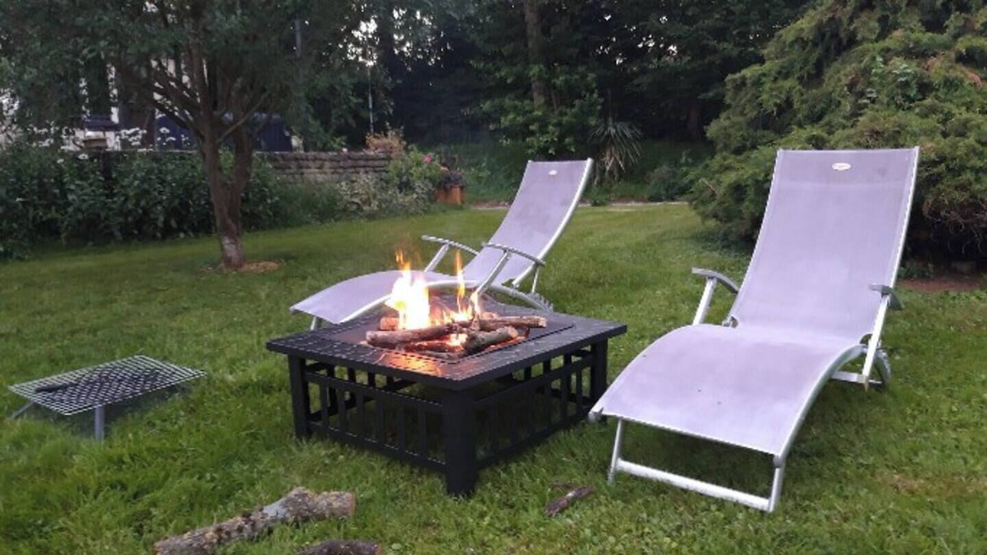 A backyard with a fire pit and two lounge chairs.