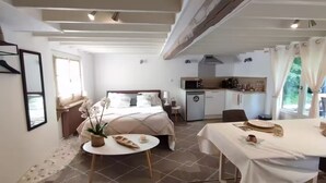 Een slaapkamer met een bed, een tafeltje en een bloempot.