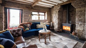 A cozy living room with a stone fireplace, a blue sofa, and a leather armchair. - Hanley House (Tenbury Wells)