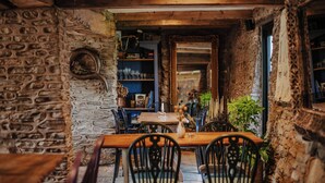 A rustic dining area with stone walls, wooden furniture, and a bookshelf. - Hanley House (Tenbury Wells)