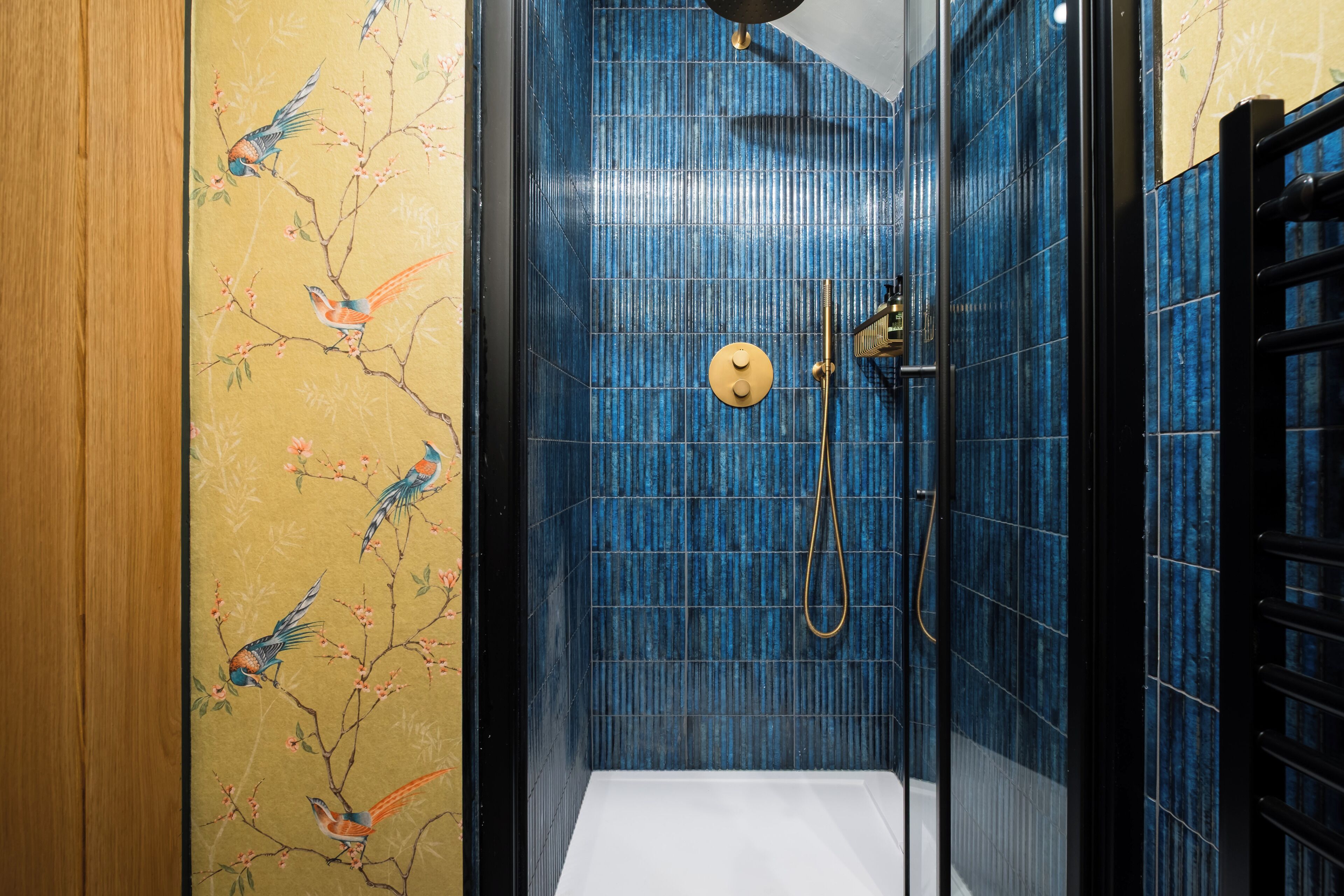 Eine Dusche mit blauen Fliesen und einer Holztür.