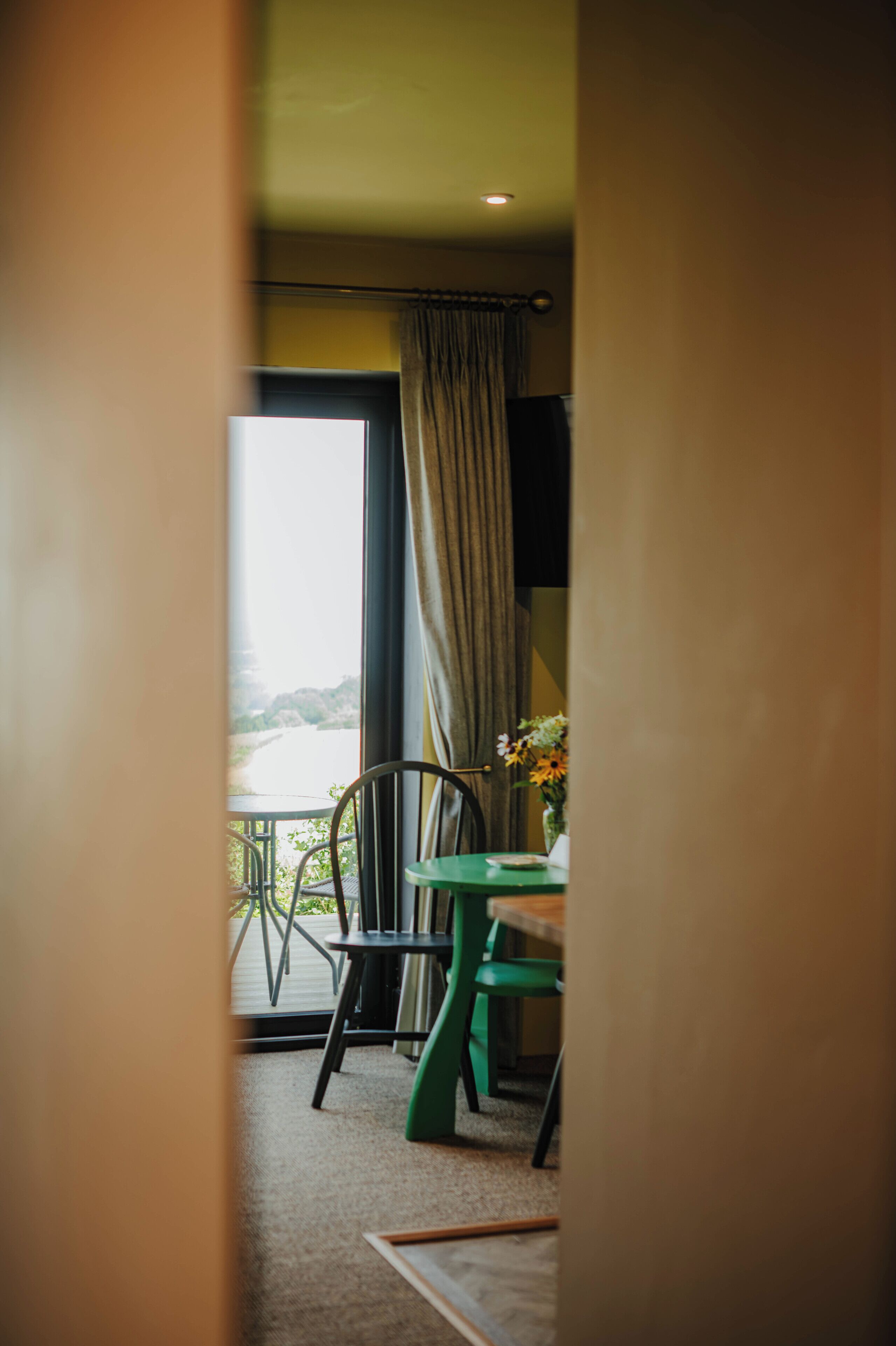 Una habitación con vista a una masa de agua, una mesa de comedor con sillas y una cortina.