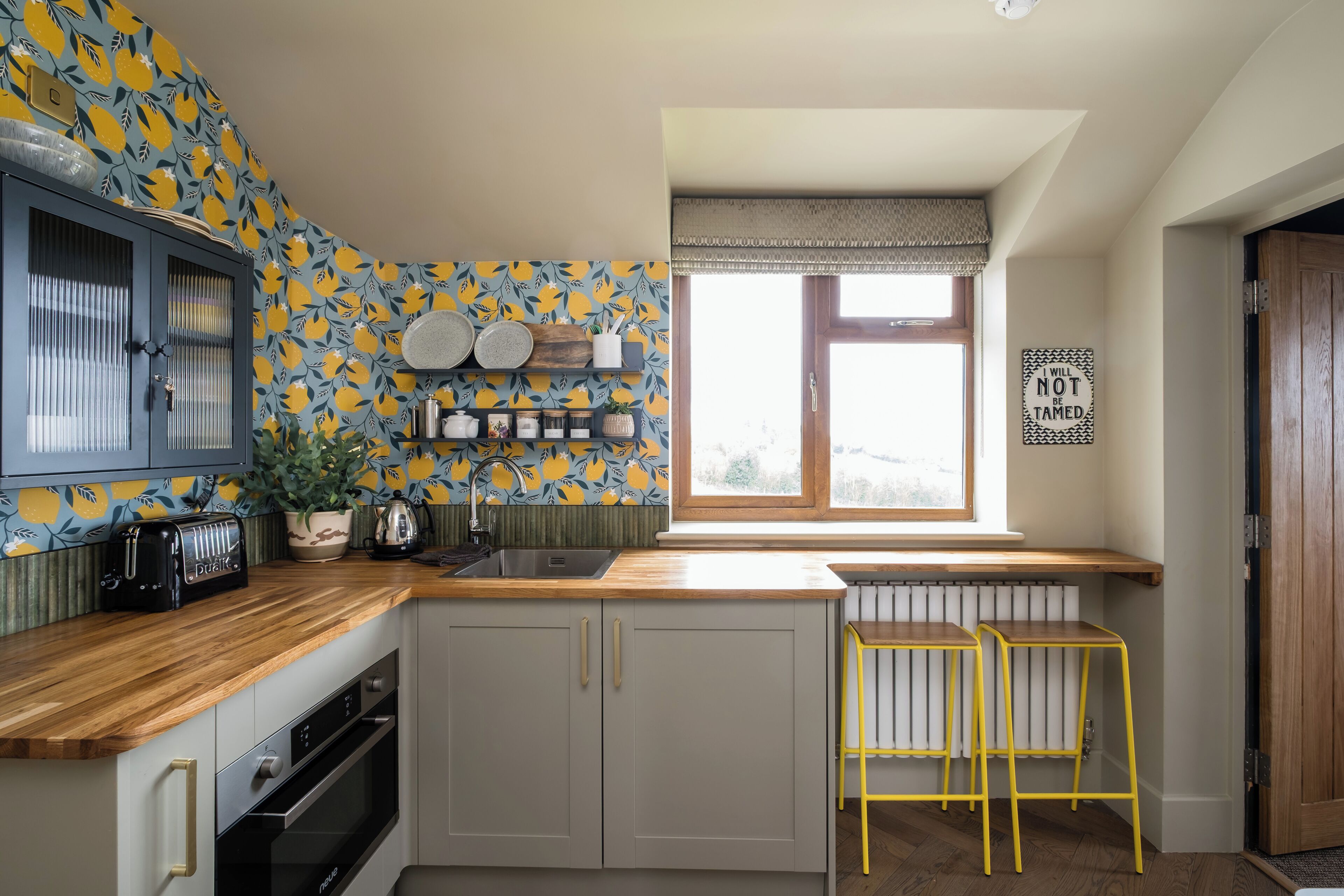 A kitchen with a window, a radiator, a toaster, and a shelf with kitchenware.