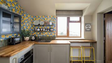 A kitchen with a window, a radiator, a toaster, and a shelf with kitchenware.