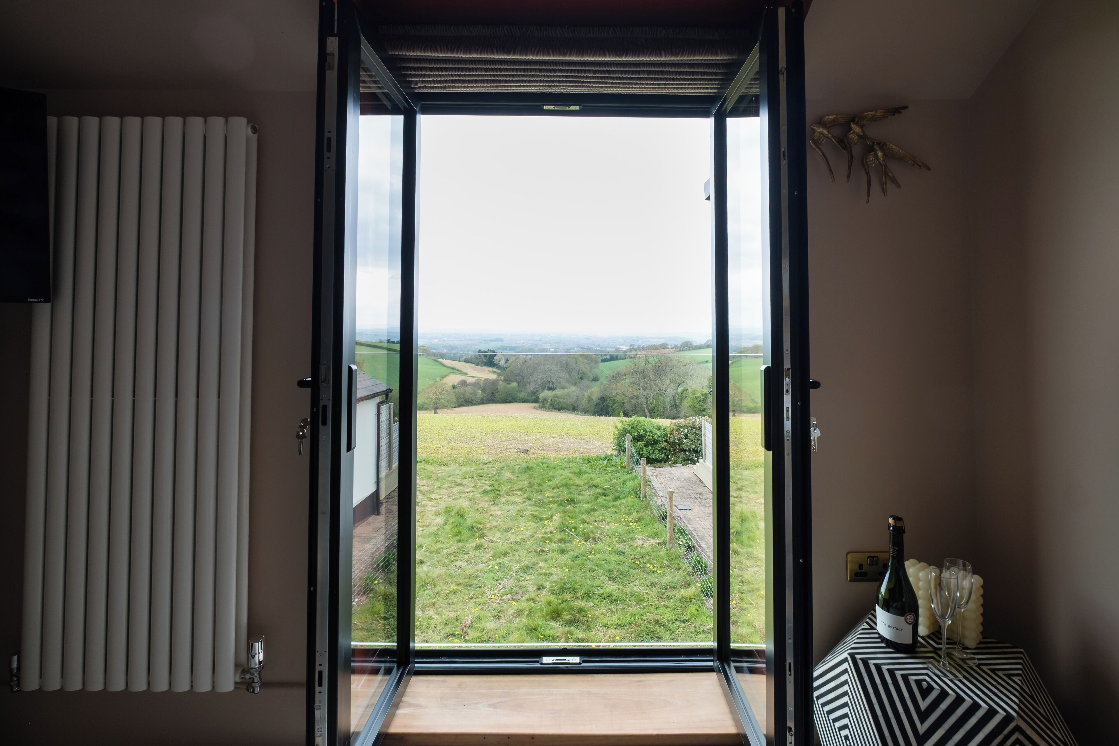 Una habitación con un gran ventanal corredizo que da a un espacio exterior con césped.