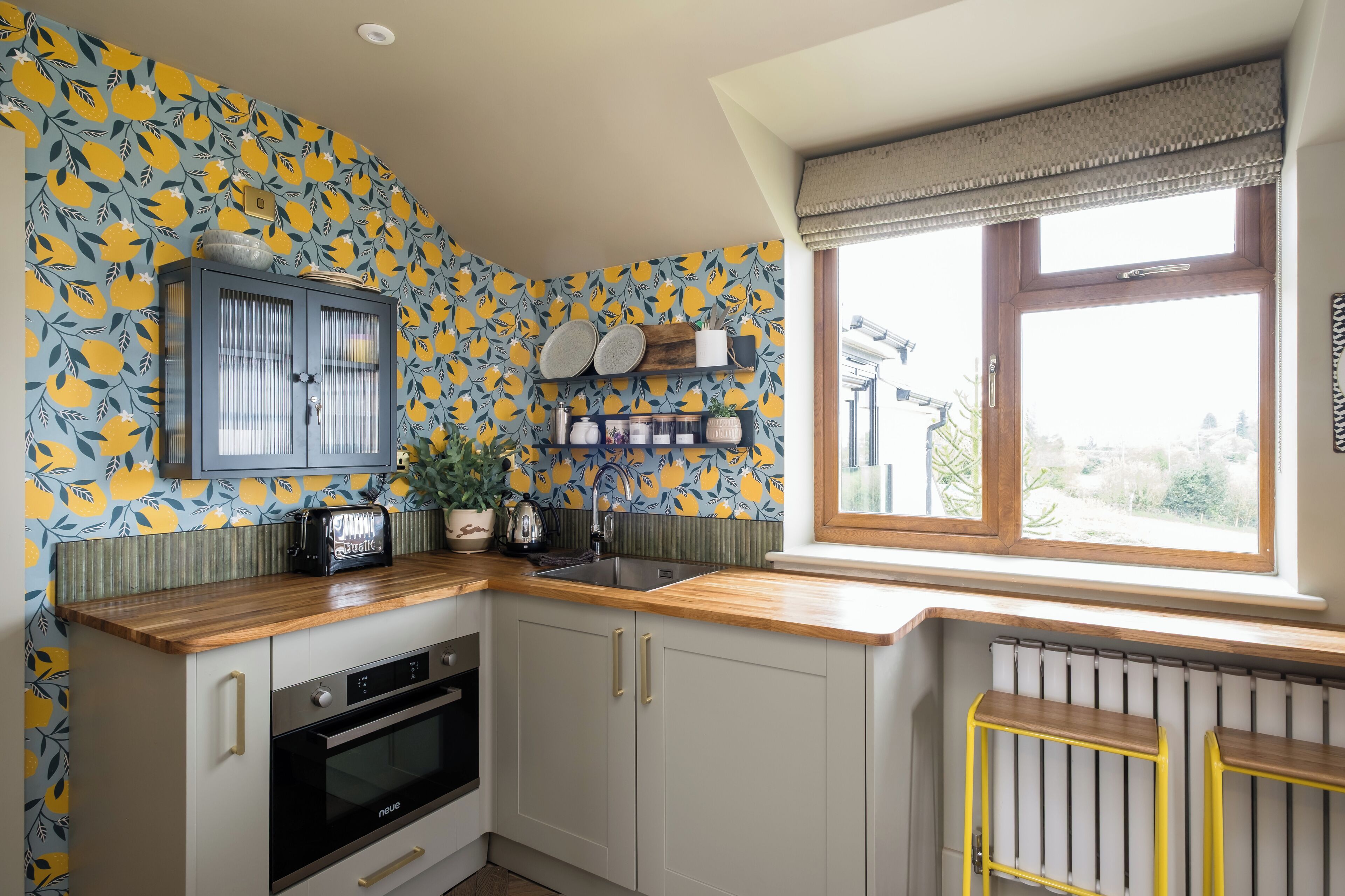 A kitchen with a wooden countertop, a built-in oven, and a window with a view of the outside.