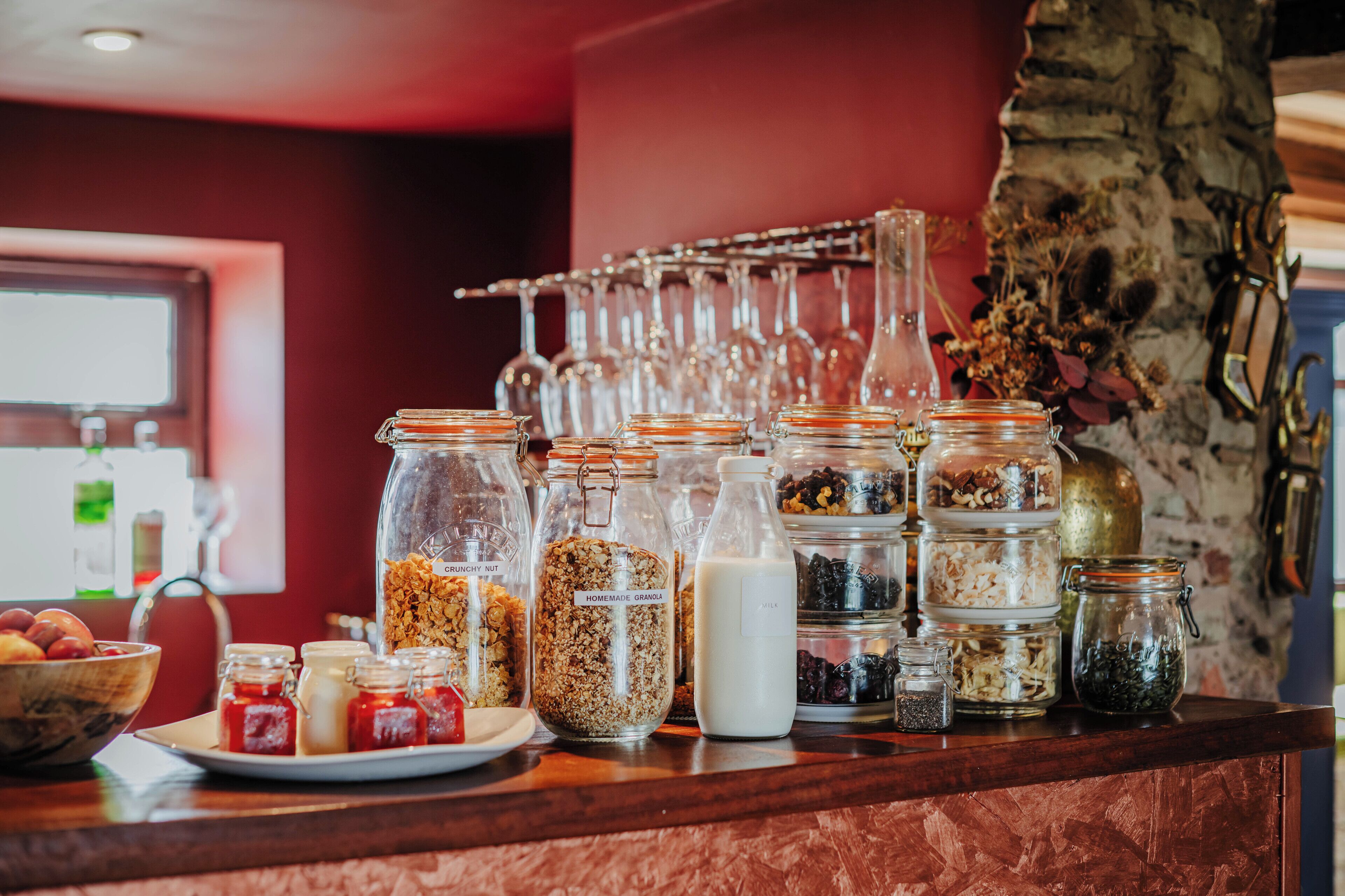 A breakfast bar with various food items and a wine rack in the background.