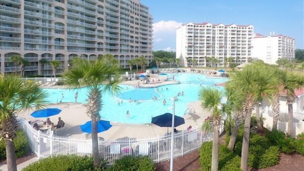 Un hotel con varios balcones, piscina y palmeras.