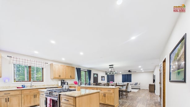 Una cocina amplia con armarios de madera, una isla central y un comedor con candelabro.
