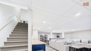 Un interior moderno con una escalera, una zona de cocina y una sala de estar con un sofá y una mesa.
