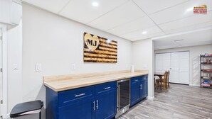 Una cocina moderna con armarios azules, encimera de madera y una obra de arte con forma de corazón que muestra las iniciales 'MJ' en la pared.