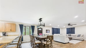 Un amplio espacio de sala con una mesa de comedor, sillas de madera, un sofá y un ventilador de techo.