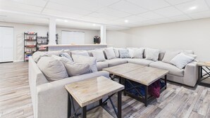 Un salón amplio con un sofá seccional en forma de L, una mesa de centro y una mesita auxiliar.