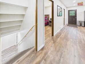 A staircase with a handrail, a door, and a wall with a framed picture.