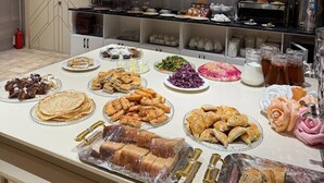 A buffet table with various food items and a clock on the wall. - Nur Makan Hotel Tashkent (Tashkent)