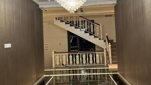 A hallway with a marble floor, a chandelier, and a staircase with a railing. - Nur Makan Hotel Tashkent (Tashkent)
