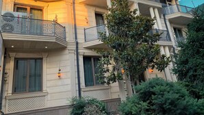 A multi-story building with balconies, decorative railings, and a tree in the foreground. - Nur Makan Hotel Tashkent (Tashkent)