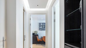 A modern hallway with a herringbone floor, glass doors, and a dark wooden cabinet. - A pop of colours (London)