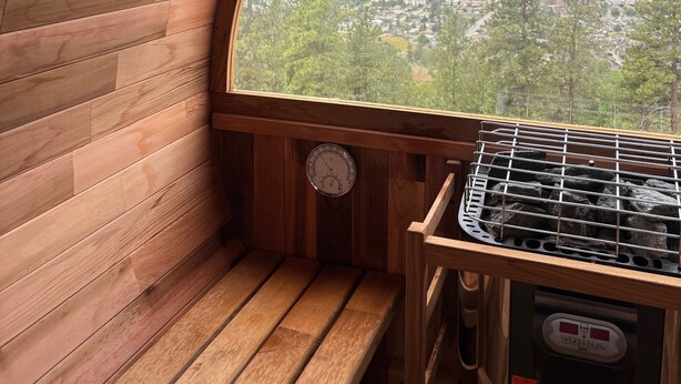 A wooden interior with a large window offering a view of a lake and mountains. - Bungalow in the Bluffs (Penticton)