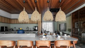 Een moderne keuken met een centraal eiland, houten stoelen en hangende lampen.