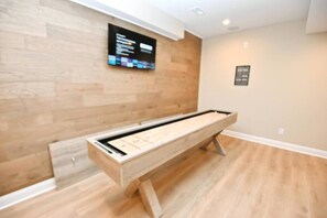 Une pièce comprenant un long banc en bois, un téléviseur fixé au mur et un panneau encadré accroché au mur.