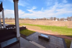 A covered outdoor area with a view of a grassy field and distant trees.