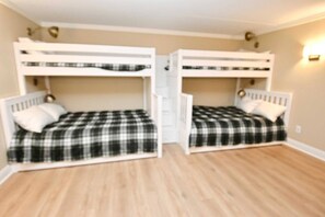 A room with two bunk beds, each with a checkered blanket and pillows.