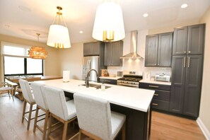 A modern kitchen with a central island, bar stools, and dark cabinetry.