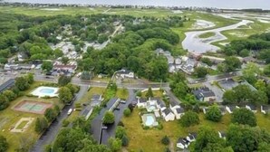 An aerial view of a residential area with houses, roads, and a large body of water in the background.