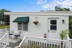 Une maison mobile blanche, dotée d’une véranda, d’une porte et d’une fenêtre.