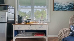 A kitchen with a microwave, coffee maker, and Scrabble game on a wooden table.