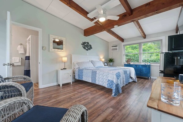 Une chambre à coucher avec un lit, des tables de chevet, un miroir et une fenêtre.