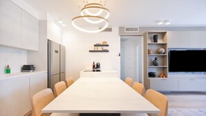 Una cocina moderna con una mesa de comedor grande, electrodomésticos integrados y un televisor.
