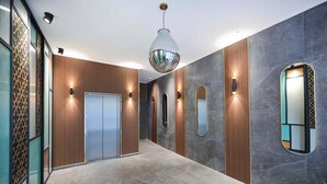 Un pasillo moderno con un panel de pared de madera, piso de mármol y una lámpara colgante.