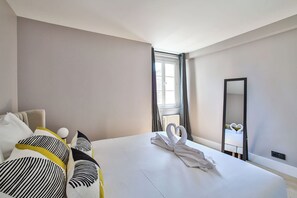 Ein Hotelzimmer mit Bett, Stuhl, Spiegel und einem fenster mit Vorhängen.