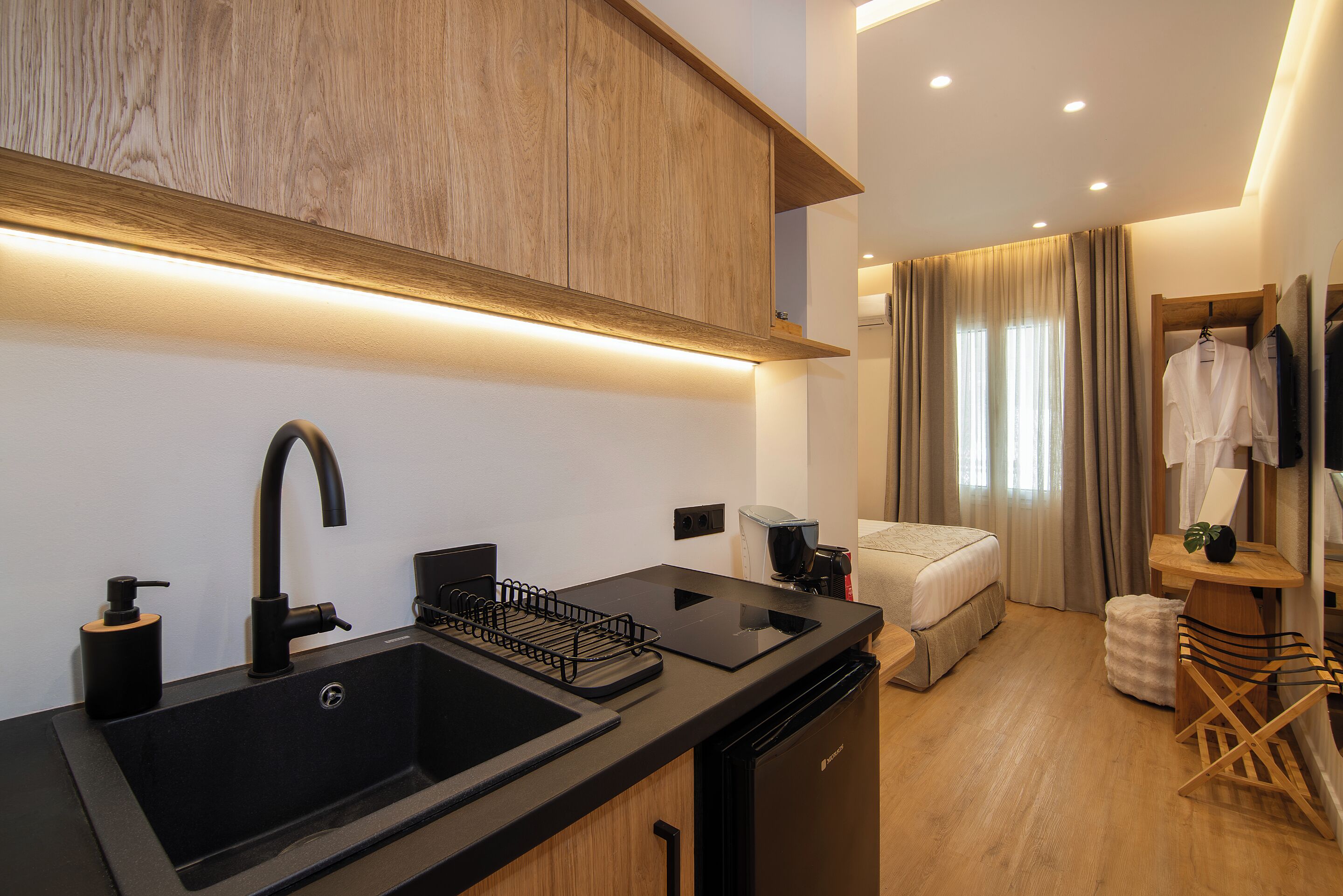 A modern kitchen with a black sink, wooden cabinets, and a compact dishwasher.