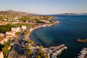 An aerial view of a coastal town with a marina, buildings, and a mountain in the background.