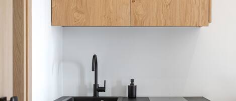 A kitchen with wooden cabinets, a black sink, and a black refrigerator.