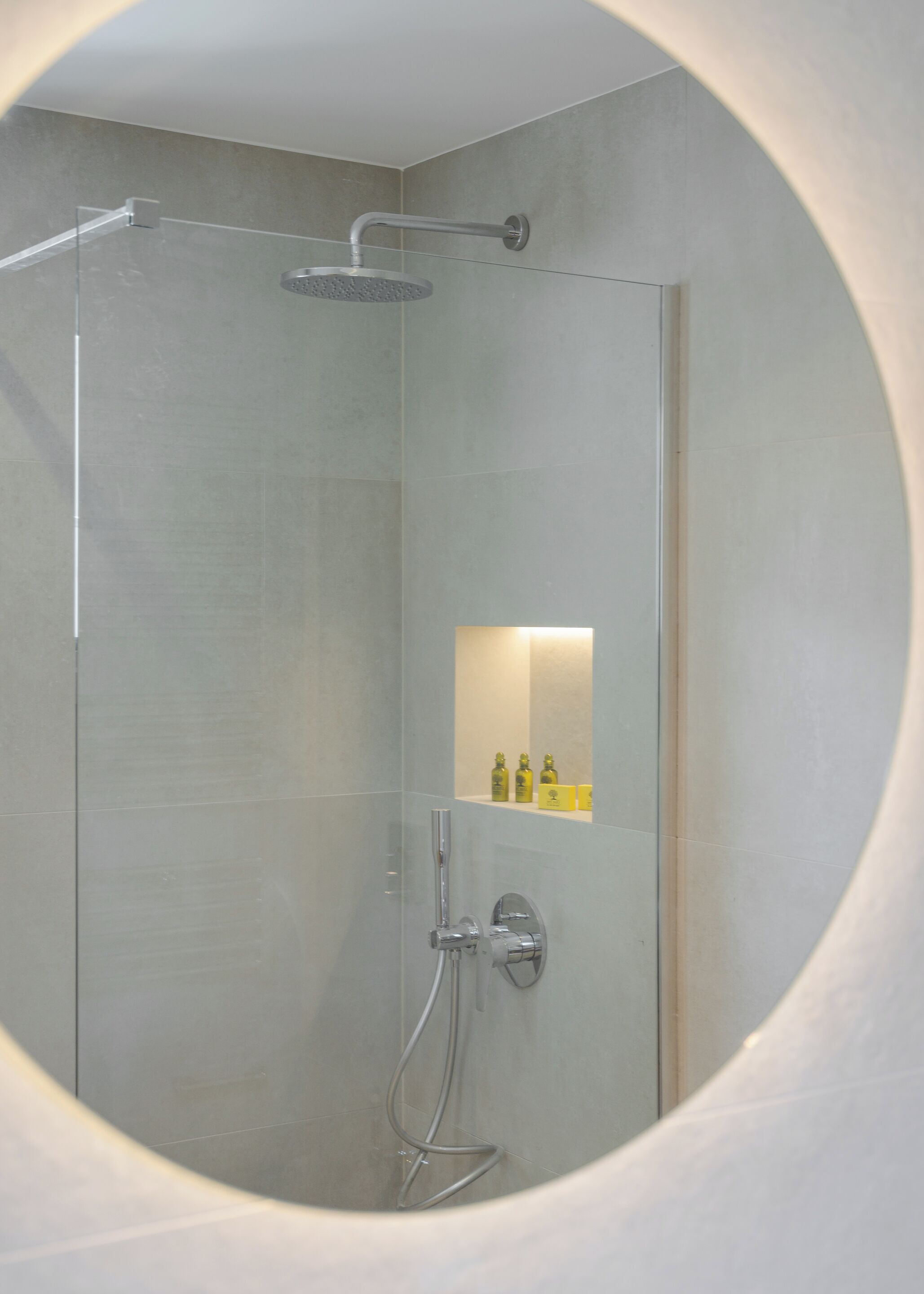A modern shower enclosure with a glass door, a handheld showerhead, and a wall-mounted faucet.